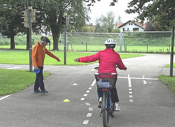 Radfahrerin beim Linksabbiegen mit Trainer